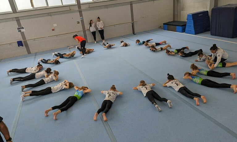 mädchen liegen im kreis und machen dehnübungen