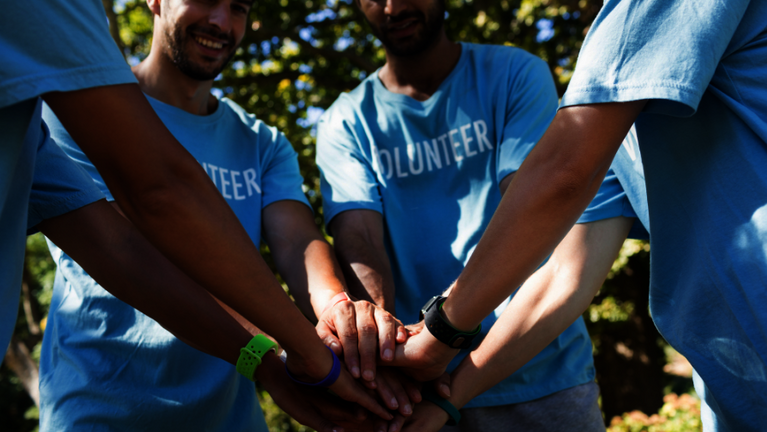 Volunteers halten ihre Hände ihn der Mitte ausgestreckt zusammen