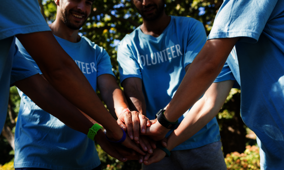 Volunteers halten ihre Hände ihn der Mitte ausgestreckt zusammen