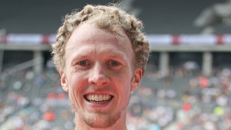 Sportler steht im Stadion und formt mit den Fingern ein Herz