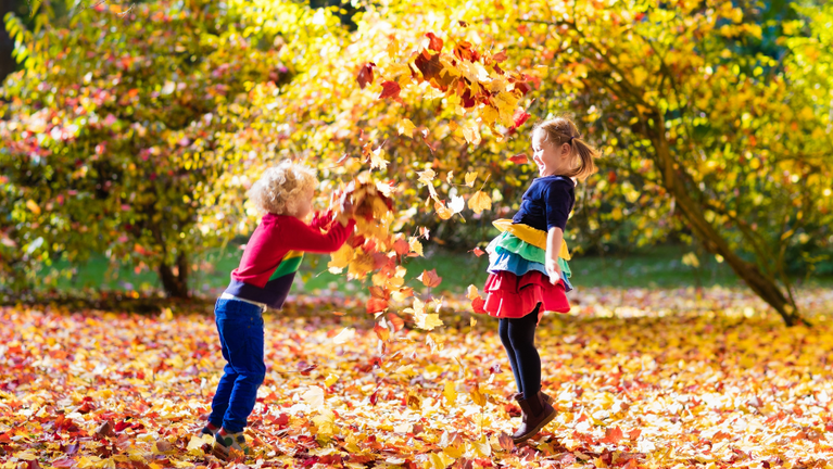 Zwei Kinder spielen im herbstlichen Laub