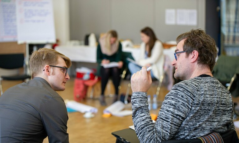 zwei sitzende Männer unterhalten sich