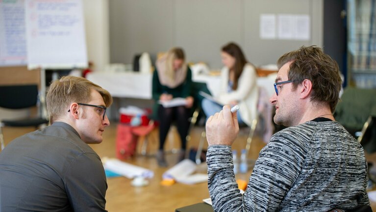 zwei sitzende Männer unterhalten sich