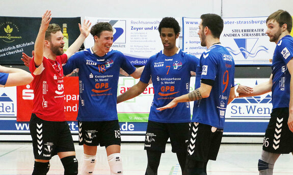 5 Volleyballspieler freuen sich über einen Punkt in der Halle