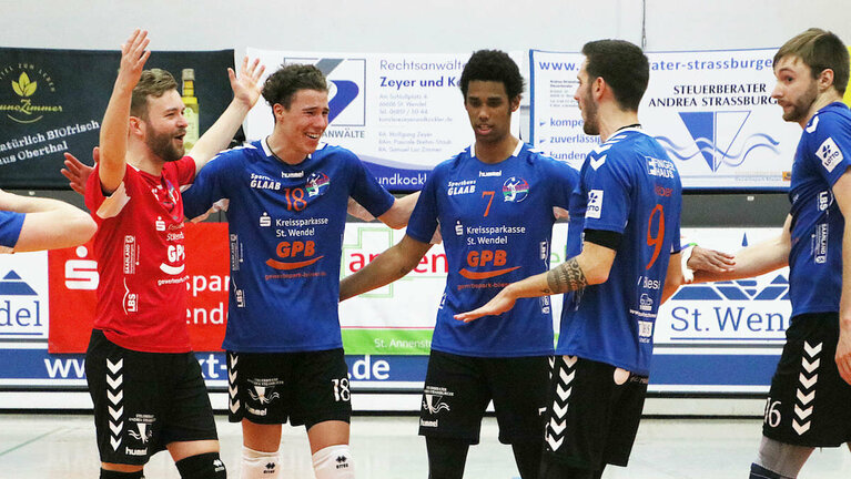 5 Volleyballspieler freuen sich über einen Punkt in der Halle