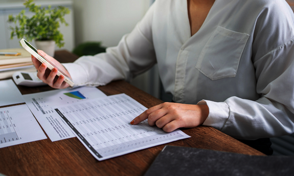 Bildausschnitt einer Frau beim Bearbeiten von Unterlagen