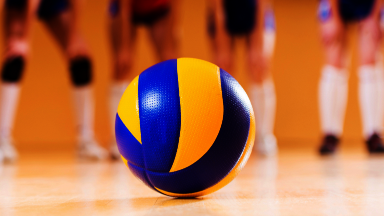 Volleyball mit Team im Hintergrund.