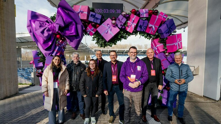 Gruppenfoto vor einem Herz-Motiv mit einem Countdown-Zähler