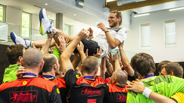 Eine Sportmannschaft jubelt und wirft vor lauter Freude ein Teammitglied hoch