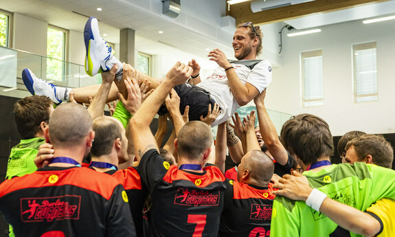 Eine Sportmannschaft jubelt und wirft vor lauter Freude ein Teammitglied hoch