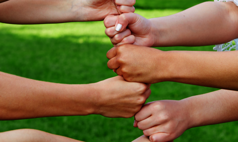 Sechs Fäuste werden mit ausgestrecktem Arm übereinander gehalten