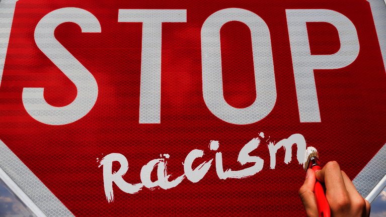Grafik mit einem Stoppschild und einer Hand, die Racism auf das Schild schreibt
