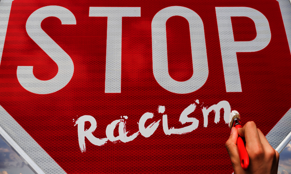 Grafik mit einem Stoppschild und einer Hand, die Racism auf das Schild schreibt