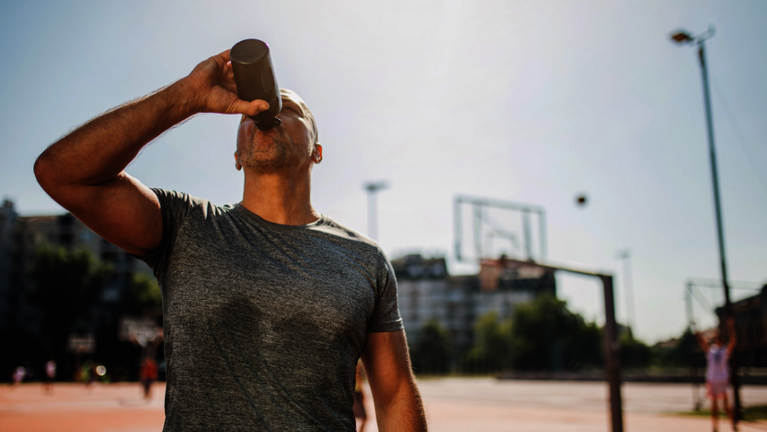 Ein Sportler auf dem Basektballplatz trinkt aus einer Trinkflasche