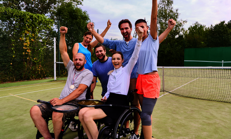 Eine inklusive Gruppe mit Tennisspieler:innen auf dem Tennisplatz.