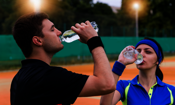 Ein Tennispieler und einen Tennisspiele trinken auf dem Tennisplatz in der Pause Wasser