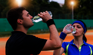 Ein Tennispieler und einen Tennisspiele trinken auf dem Tennisplatz in der Pause Wasser