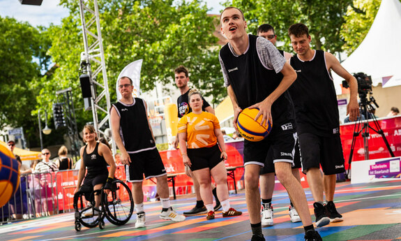 Sportler mit und ohne Behinderung spielen Basketball