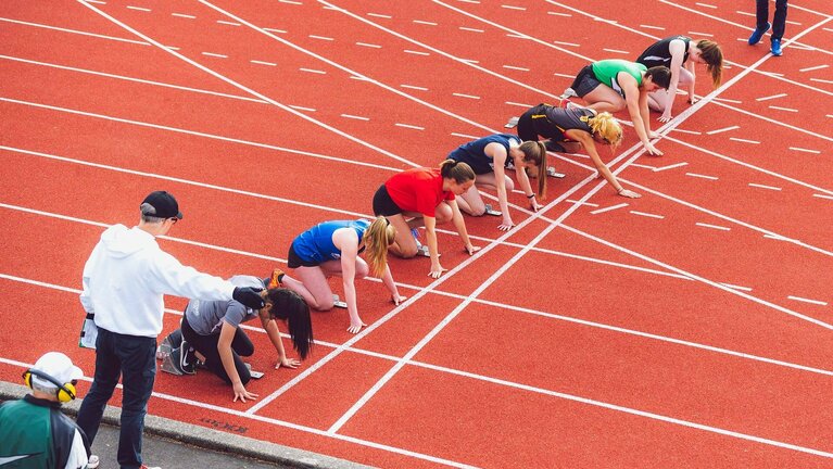 Läufer in Startposition auf der Laufbahn.