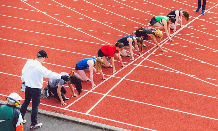 Läufer in Startposition auf der Laufbahn.
