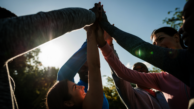Eine Gruppe von Sportlern klatscht mit erhobenen Armen ab