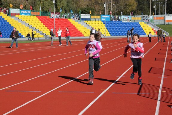Kinder laufen auf der Leichtathletik-Bahn.