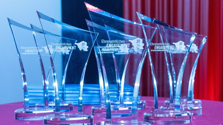 glänzende Ehrenamtspreise stehen auf einem Tisch und warten auf ihren Gewinner
