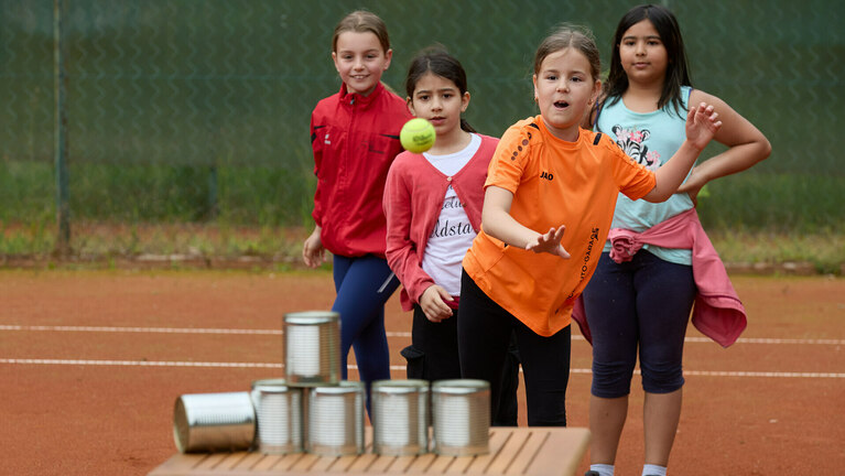 TW220192.jpg Vier Mädchen spielen auf dem Sportplatz ein Wurfspiel mit Dosen