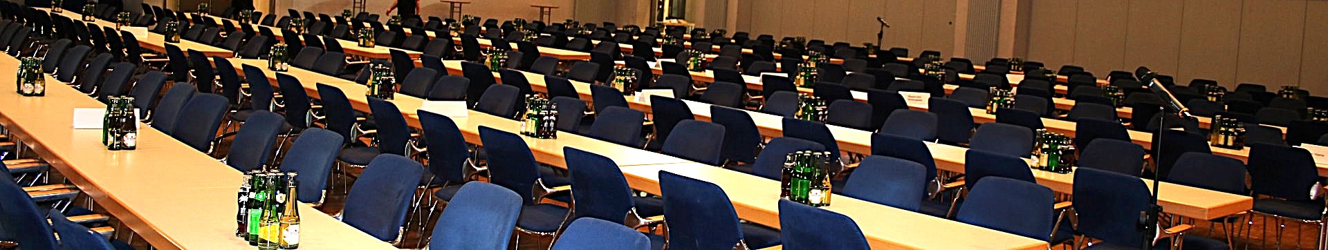 Mehrere Reihen von Tischen und Stühlen in einer Halle